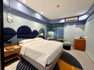a bedroom with a large white bed and blue walls at Ibis Styles Subic in Olongapo