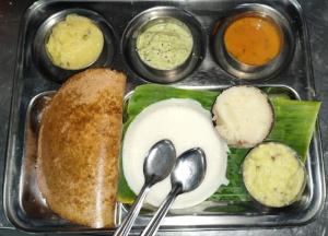 a tray of food with spoons and bread and dips at Hotel surya dev residency in Bangalore