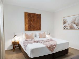 a white bedroom with a bed with a blanket on it at The Sebel Byron Bay in Byron Bay