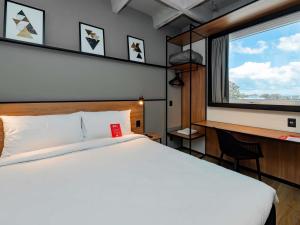 a bedroom with a white bed and a window at ibis Pelotas - Recem inaugurado in Pelotas