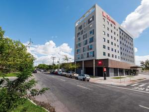 a tall white building on a street with cars parked at ibis Pelotas - Recem inaugurado in Pelotas