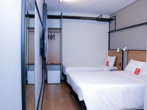a bedroom with two beds and a television in it at ibis Primavera do Leste in Primavera do Leste