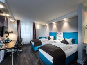 a hotel room with two beds and a desk at ibis Styles Cologne Airport in Troisdorf +49 photos