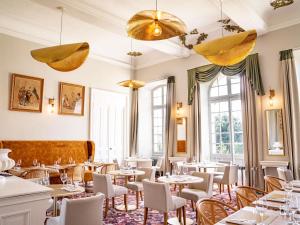 a restaurant with tables and chairs and windows at Château de Mazan - Handwritten Collection in Mazan