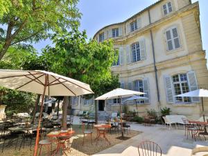 a group of tables and chairs with umbrellas in front of a building at Château de Mazan - Handwritten Collection in Mazan