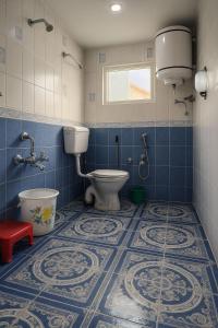 a bathroom with a toilet and a window and blue tiles at Heritage Rose Inn in Srinagar