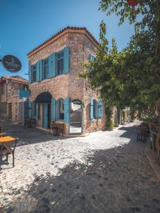 a brick building with blue windows on a street at Casa Alegre Alaçatı in Alaçatı