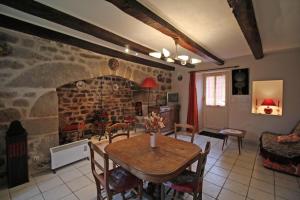 a living room with a table and a stone fireplace at La bachellerie in Nedde +6 photos