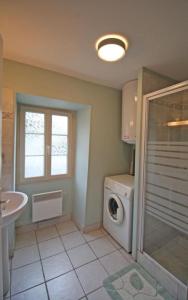 a bathroom with a washing machine and a sink at La bachellerie in Nedde