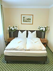 a bed in a bedroom with two vases with flowers at Pensjonat BELVEDERE in Szczyrk +8 photos