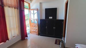 a living room with a television and a cabinet with a door at DreamCatcher & Homestay in McLeod Ganj