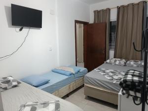 a bedroom with two beds and a flat screen tv at Suítes Monte Cristo II in Aparecida