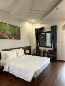 a bedroom with a large white bed and chairs at Hotel ĐÁ ĐỎ in Danang