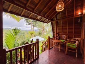 a porch of a wooden cabin with a table and chairs at Casa Vella Cottages by AGATA in Bedugul