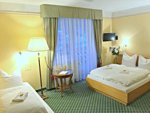 a hotel room with two beds and a table and a lamp at Pensjonat BELVEDERE in Szczyrk