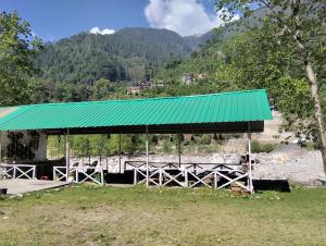 a shelter with a green roof in a field at Ambika Campaign Huts in Manāli