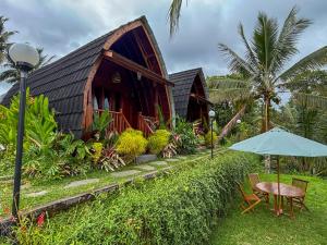 a wooden house with a table and an umbrella at Casa Vella Cottages by AGATA in Bedugul