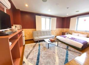 ein Schlafzimmer mit einem Bett, einer Couch und einem Fernseher in der Unterkunft ホテルスズカ in Matsudo