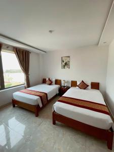 a hotel room with two beds and a window at Flamengo hotel in Dong Hoi