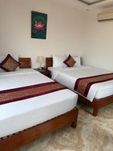 two beds sitting next to each other in a room at Flamengo hotel in Dong Hoi