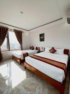 a hotel room with two beds and a window at Flamengo hotel in Dong Hoi