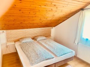 a bed in a room with a wooden ceiling at Levendula apartman in Kehidakustány