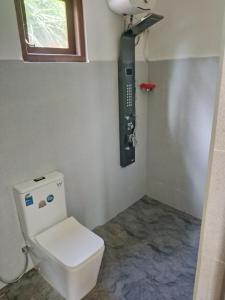 a bathroom with a toilet with a phone on the wall at Lush Home in Bandarawela