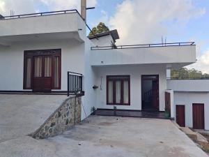 a white house with two doors and a patio at Lush Home in Bandarawela