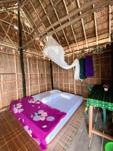 a bed in a thatched room with a table at Sunrise Raja Ampat in Besir