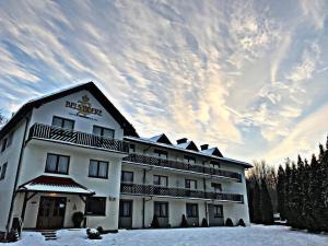 a large white building with snow on the ground at Pensjonat BELVEDERE in Szczyrk