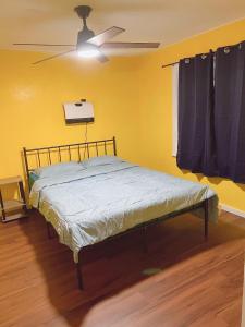 a bed in a yellow room with a ceiling fan at Pet friendly Newly renovated Two bedroom Property in Central Okc in Oklahoma City
