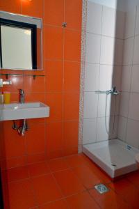an orange and white bathroom with a shower and a sink at krystallia apartments in Dassia