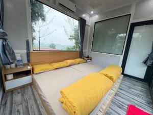 a room with yellow pillows and a large window at Cỏ Mây Wonder Homestay in Mộc Châu
