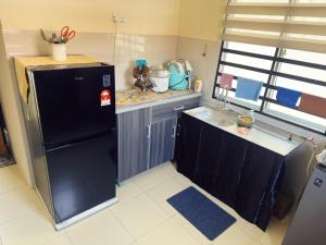 a small kitchen with a black refrigerator and a sink at Teratak Raya in Tanjung Rambutan
