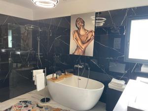 a bathroom with a tub and a painting of a woman at Villa Bois d'Argent in Lagraulière +22 photos