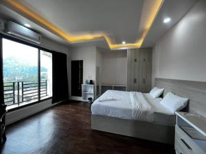 a bedroom with a bed and a large window at The View Hotel Falkland in Āīzawl
