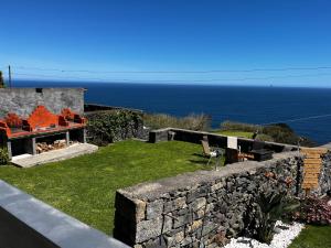 a garden with a stone wall and the ocean at Oásis Fonte Grande in Santo António