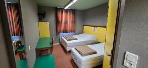 a small room with two beds and a window at Hôtel Siatel Besançon Chateaufarine in Besançon