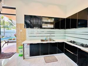 a kitchen with black cabinets and a sink at Arden Villa Quy Nhơn in Quy Nhon