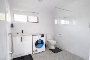 a white bathroom with a toilet and a washing machine at Waters Edge in Urangan