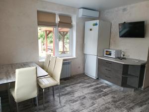 a kitchen with a refrigerator and a table and chairs at Дом с подогреваемым бассейном in Liski