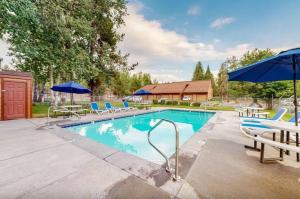 a swimming pool with chairs and umbrellas at Golf Course Retreat - Pool Access Lake Views in McCall