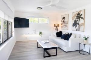 a white living room with a white couch and a table at Lakeside Views in Urangan