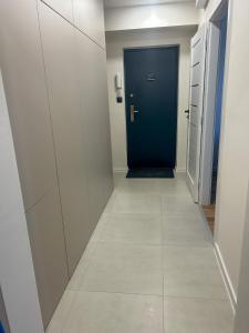 a hallway with a blue door and a tile floor at Apartmán JT in Vyšné Opátske