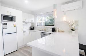 a white kitchen with white cabinets and a white refrigerator at Lakeside Views in Urangan