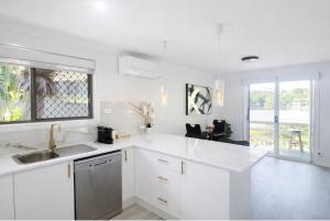 a white kitchen with a sink and a window at Lakeside Views in Urangan +9 photos