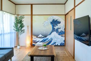 a living room with a painting of a wave at ひなたの宿結 in Miyazaki