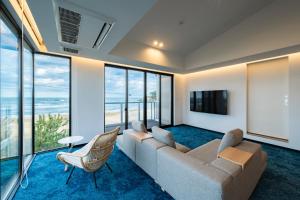 a living room with a couch and a tv and windows at KITAMAE BASE Kaga Hashitate in Kaga