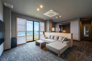 a living room with a couch and a view of the ocean at KITAMAE BASE Kaga Hashitate in Kaga