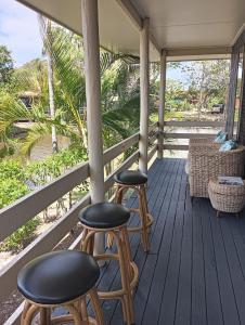 two chairs and two stools on a porch at Lakeside Views in Urangan
